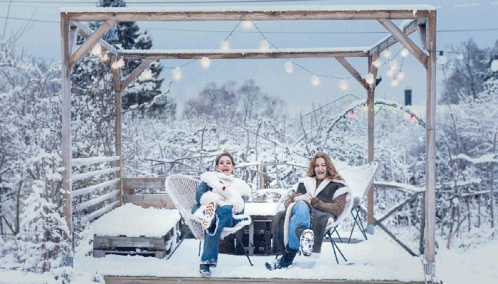 Helen Sjöholm och Anna Stadling sitter utomhus vintertid, i snöig omgivning.