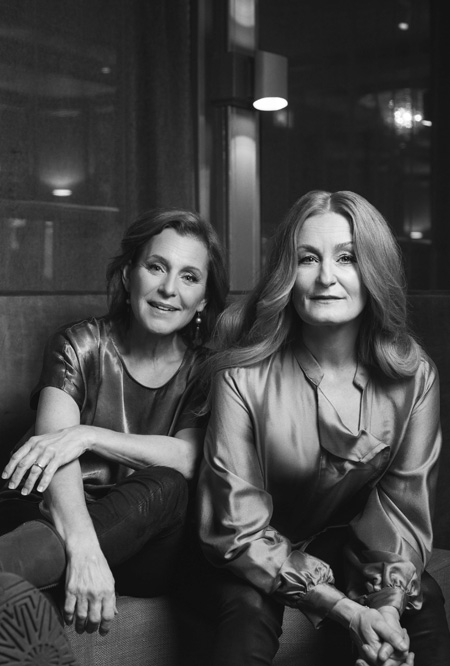 Helen Sjöholm and Anna Stadling sitting next to each other in glossy blouses. Black and white photo.