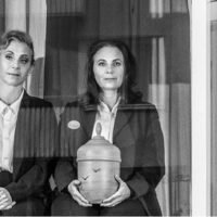 Helen Sjöholm och Anna Fahlstedt sitter på stolar i ett fönster. Pressbild i svartvitt för "Närmast sörjande".